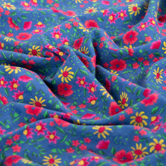 Feincord mit gelben, roten und pinken Blumen und grünen Blättern auf blauem Hintergrund vom Buntspecht Shop